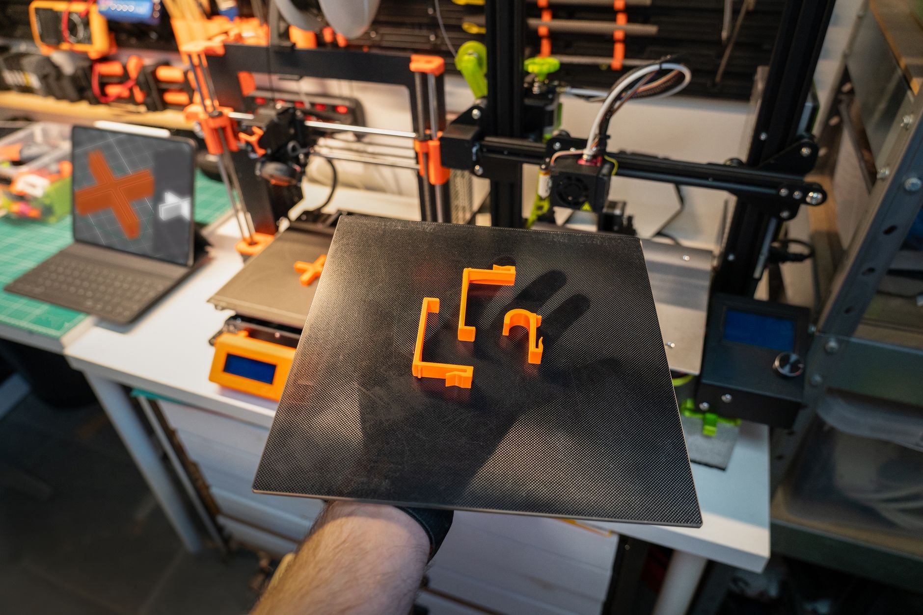 Close-up of a 3D printer and printed parts in a modern workshop setting.